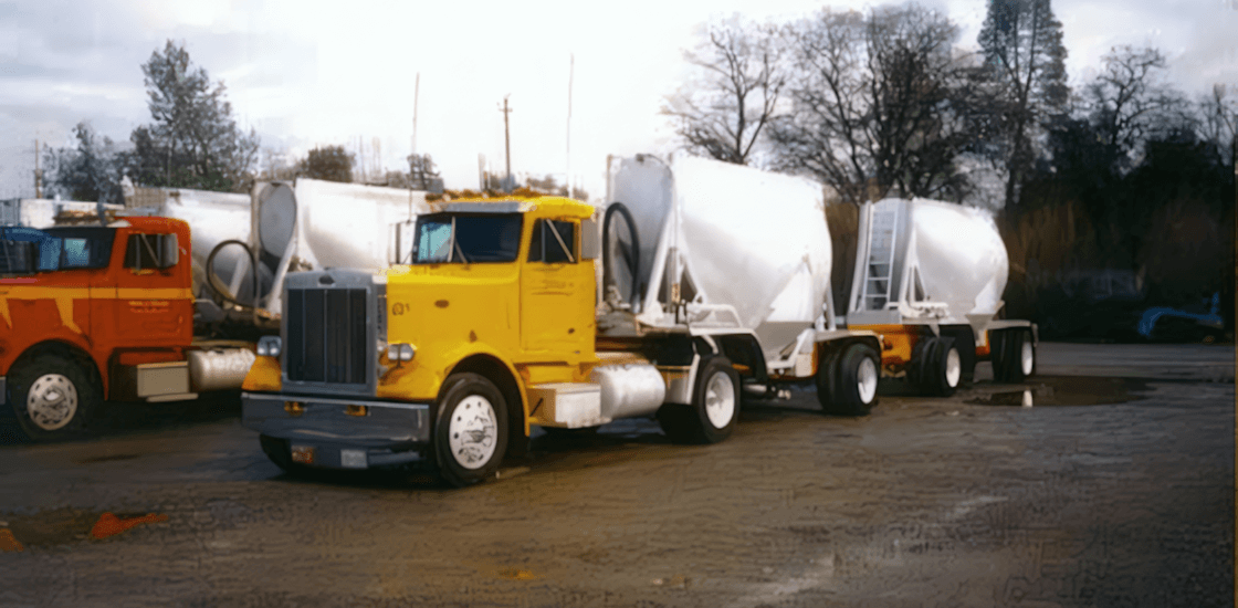 A yellow Muse Trucking truck hauling storage tanks